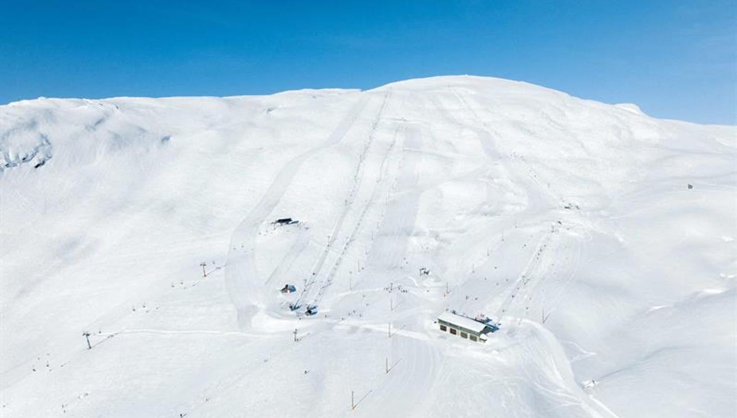 Groomed ski slopes and lifts at Røldal Ski Resort under a blue sky and sparkling snow.
