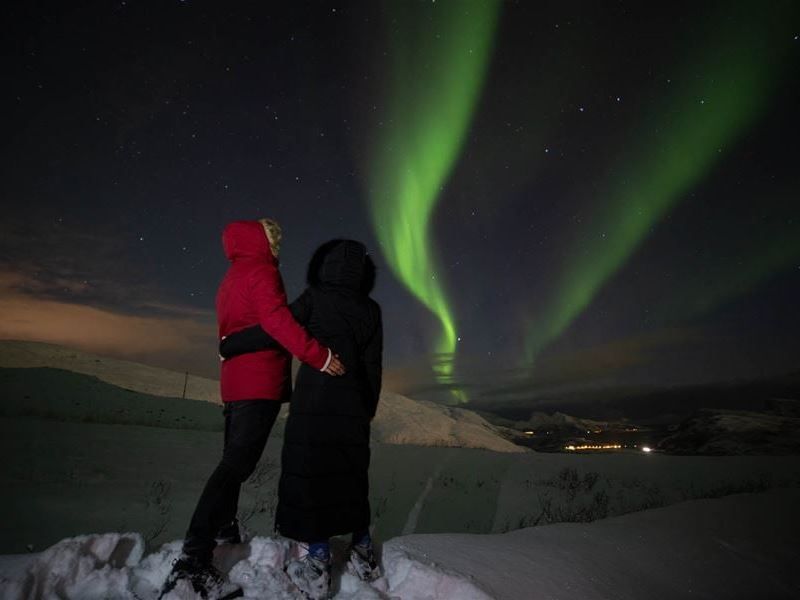 To gjester som holder hverandre og ser på nordlyset