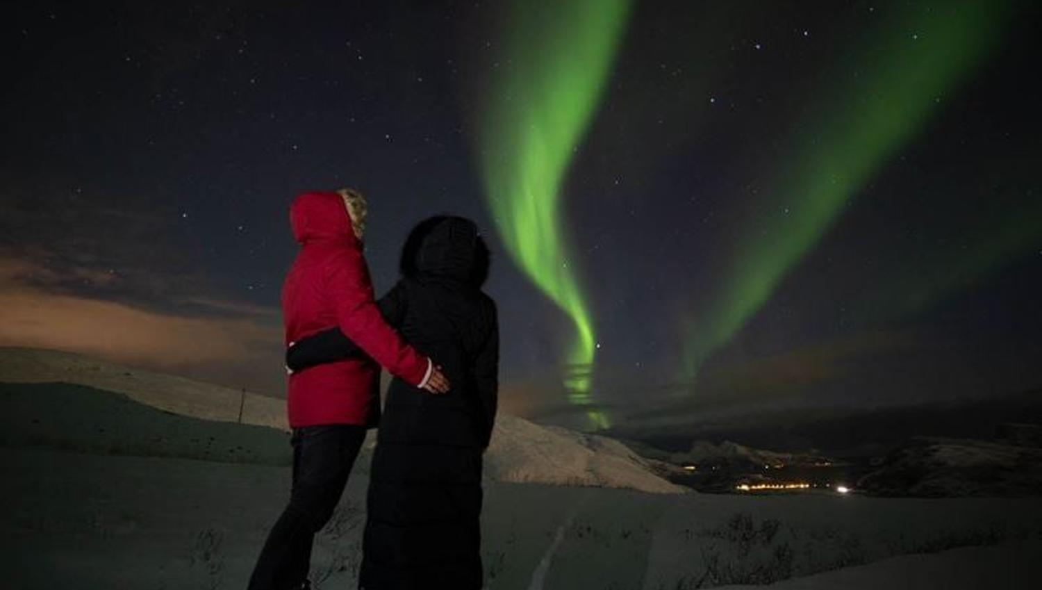 To gjester som holder hverandre og ser på nordlyset