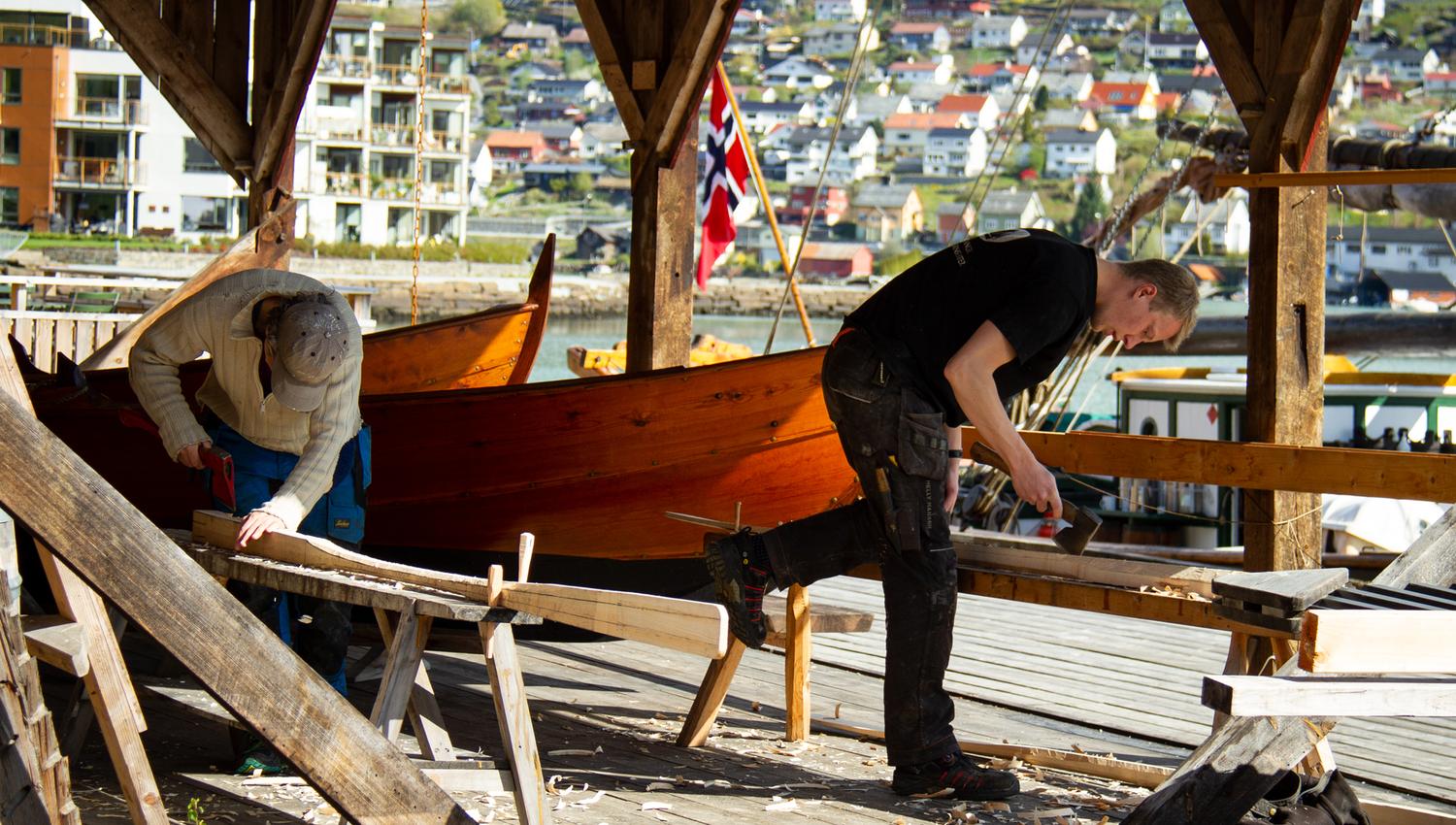 Two craftsmen working on restoring a wooden boat at Hardanger Maritime Center.
