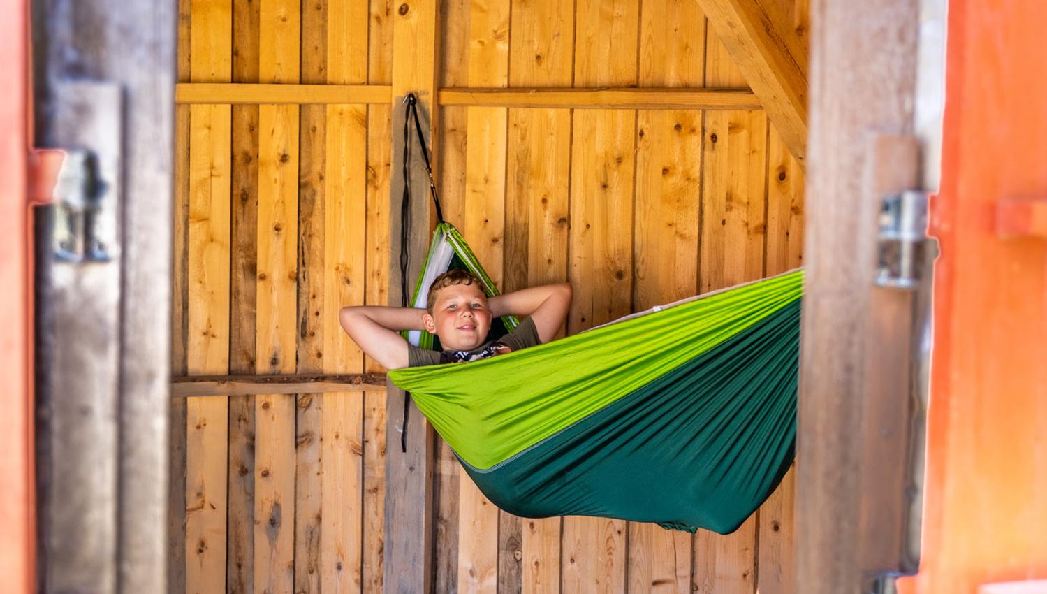 gutt i hengekøye i hytte