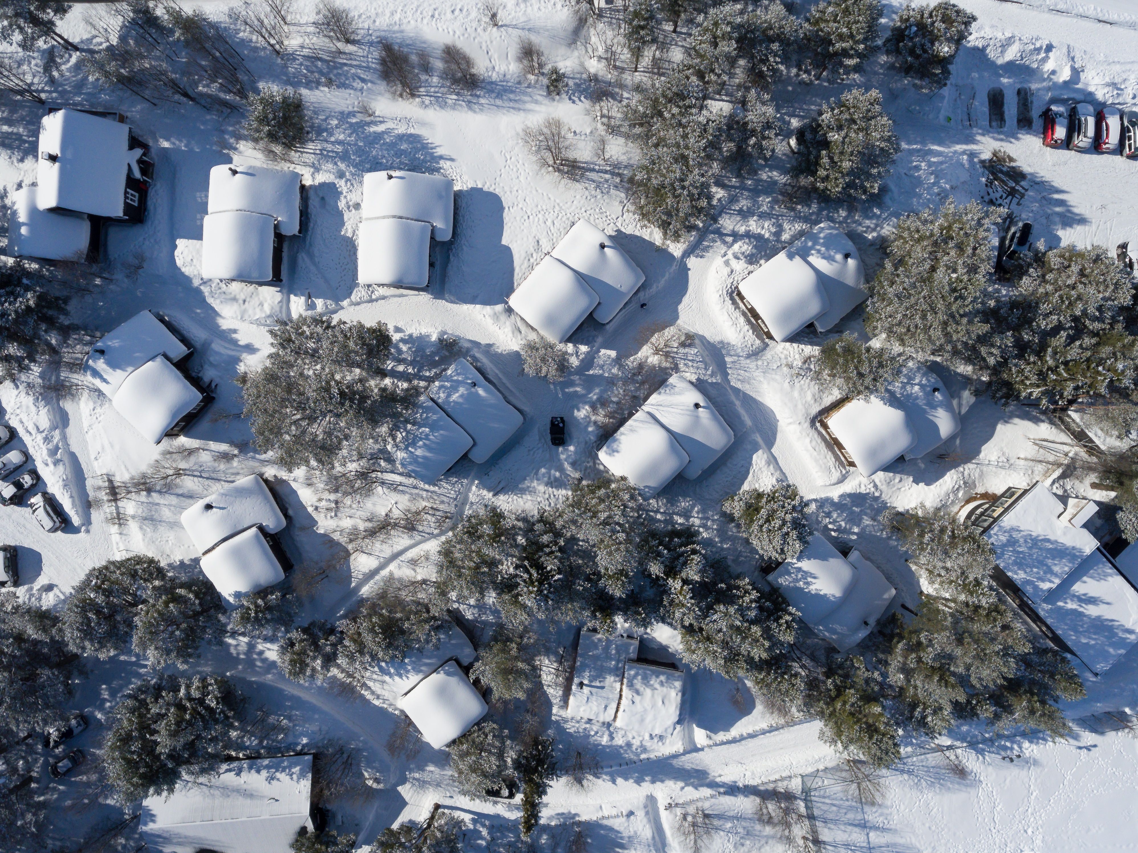 Picture from above of the cabin area in forest covered with snow. 