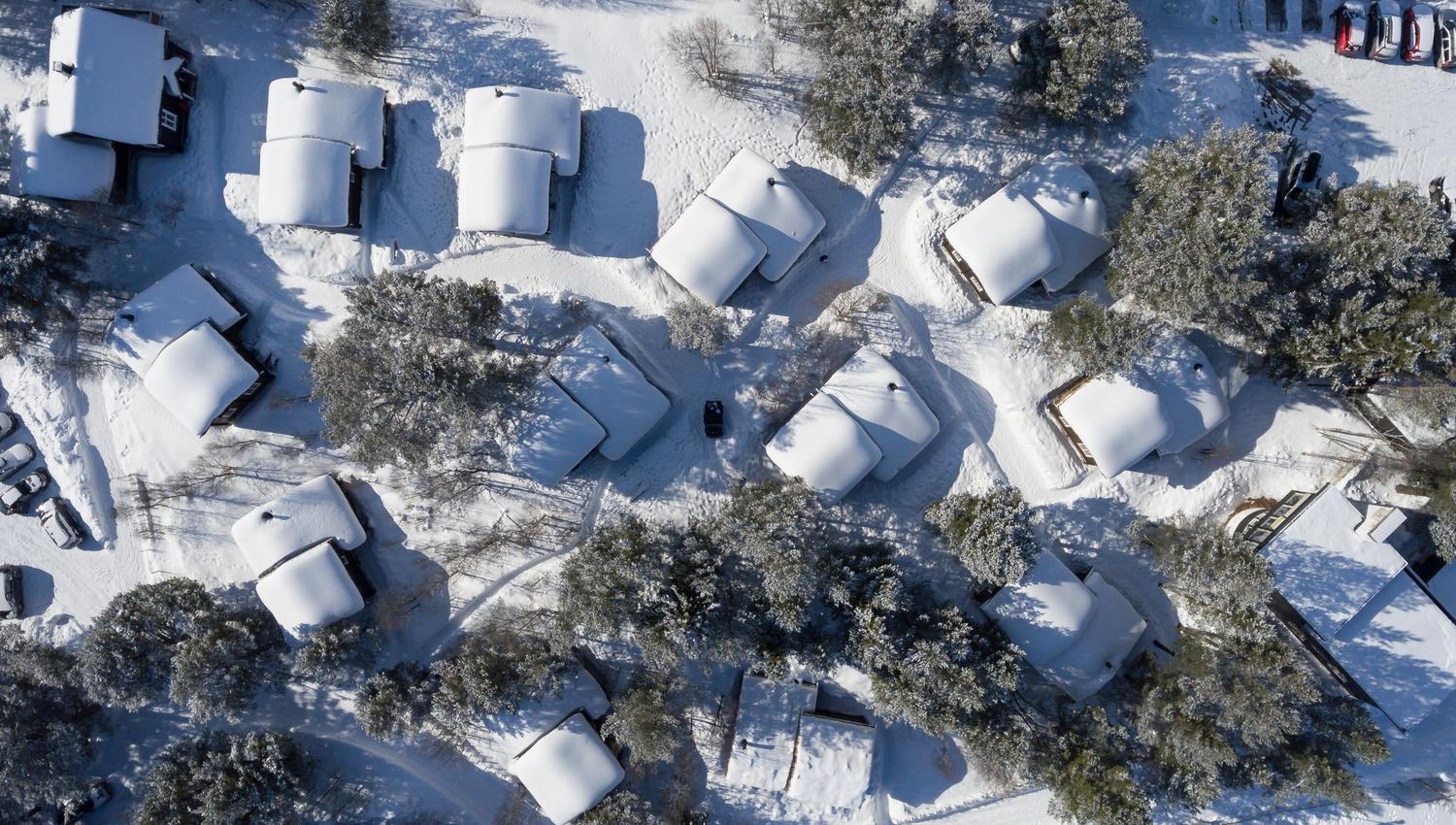 Picture from above of the cabin area in forest covered with snow.