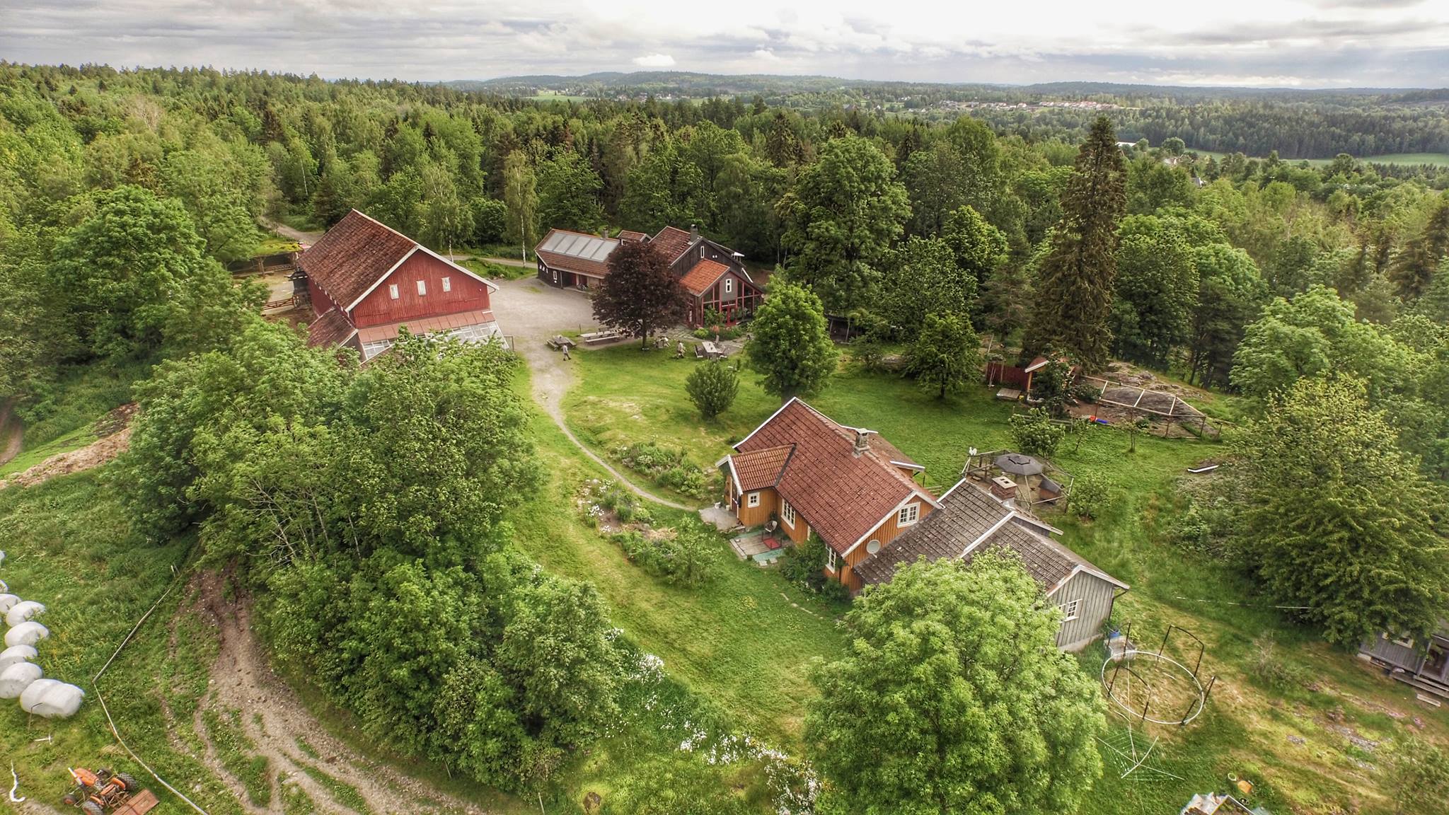 Farmhouse with four buildings and green forest around.
