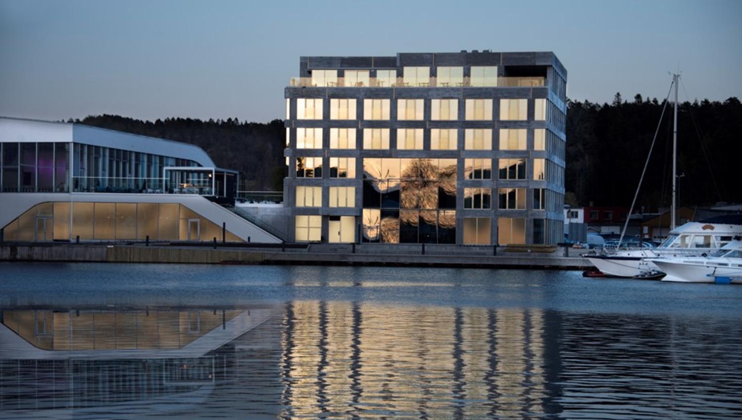 Fasade Mandal Hotel, som speiler seg i Mandalselva ved siden av Buen Kulturhus