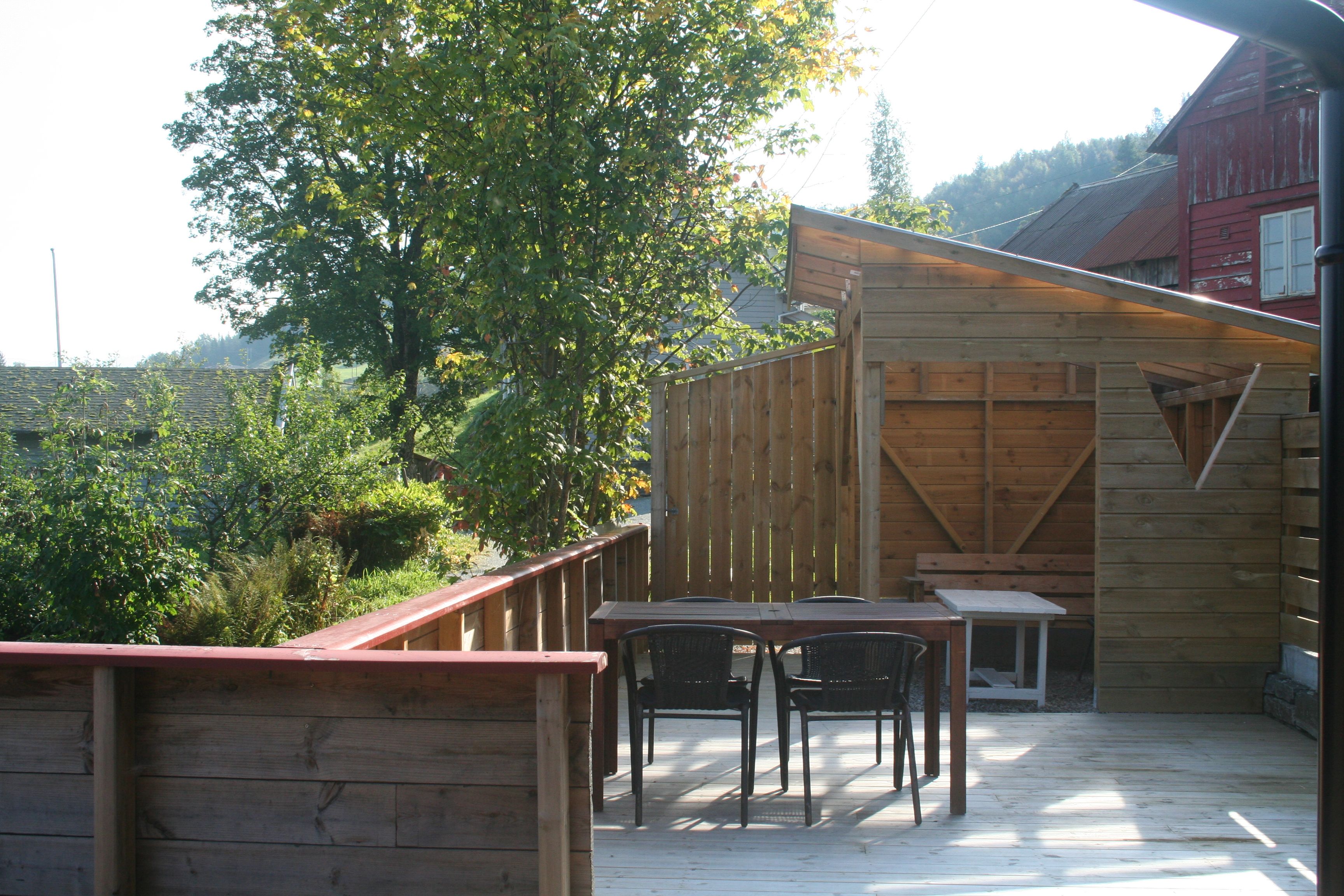 Solrik uteplass med sittegruppe og tre rundt ved Vågen Rom og Hytteutleige.