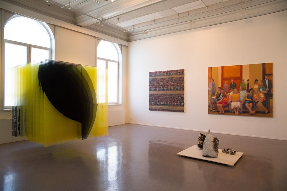 Utstilling i Kunstbanken - Kunstinstallasjon med hengende gule tråder og malerier i bakgrunnen.
