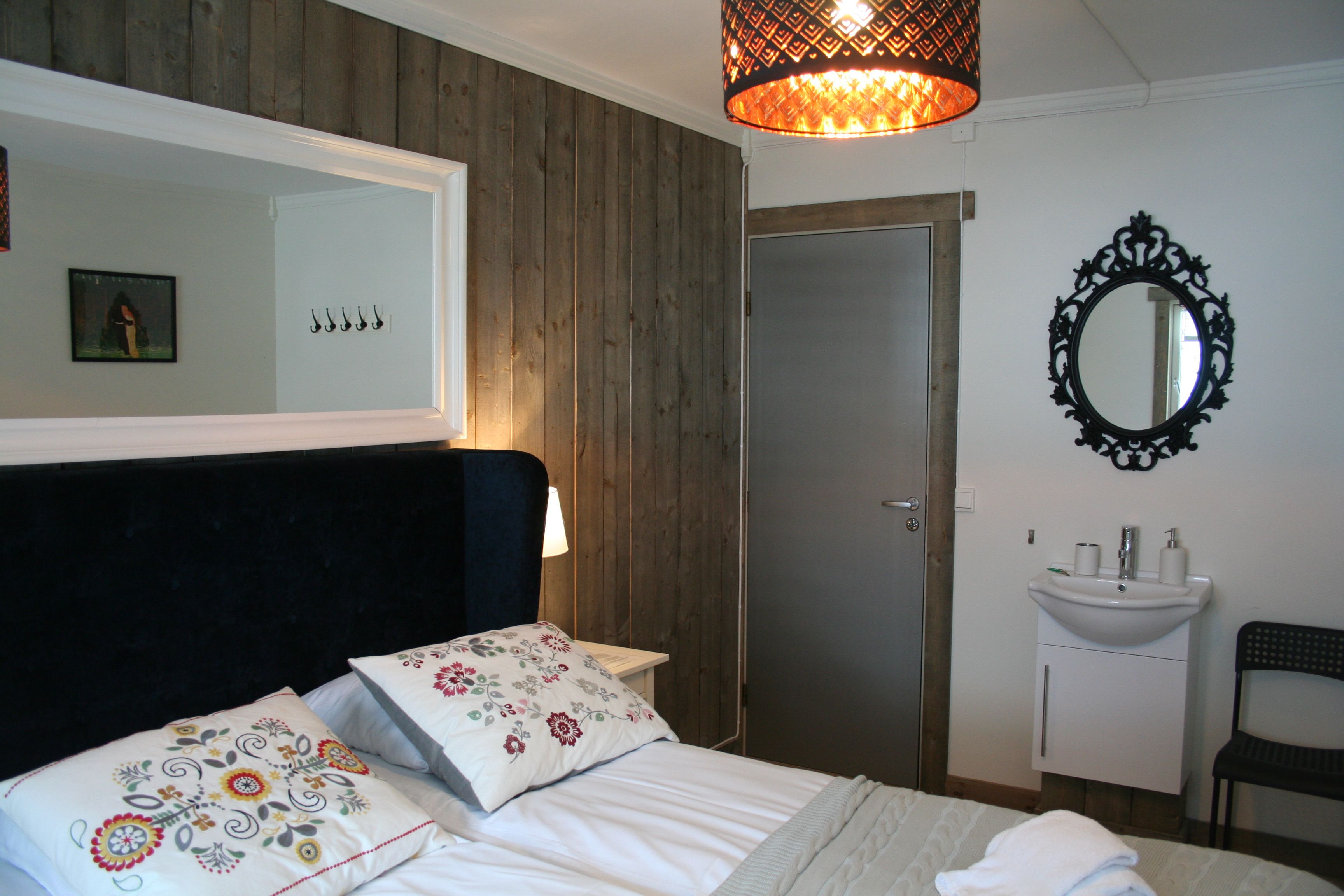 Lyst og triveleg rom på Kvamseter Lodge med klassisk interiør og veggspegel.