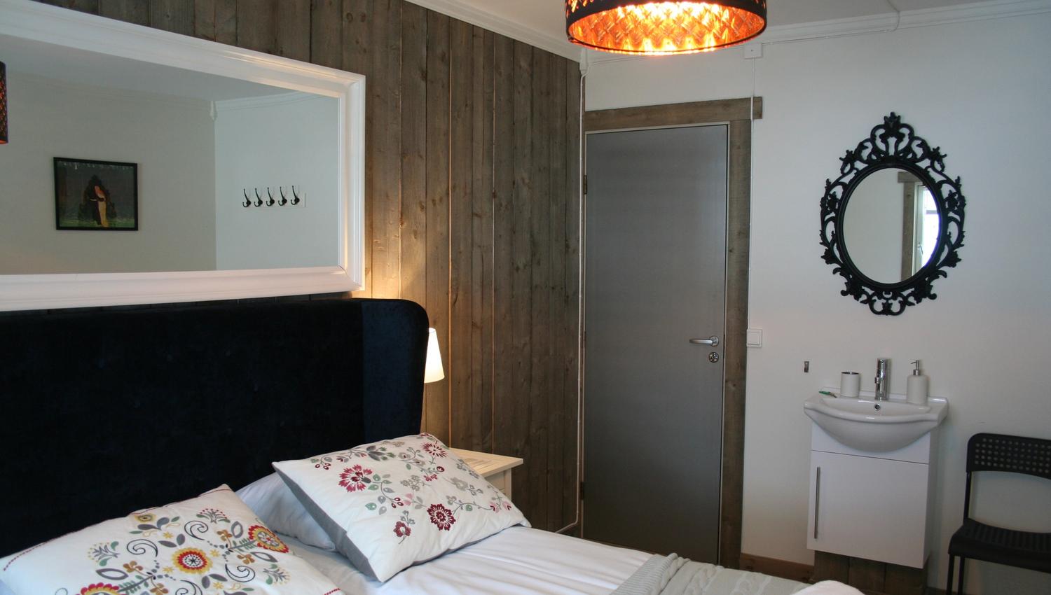 Lyst og triveleg rom på Kvamseter Lodge med klassisk interiør og veggspegel.