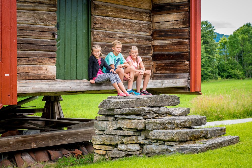 barn sitter foran en låve på Henrik Ibsen museum