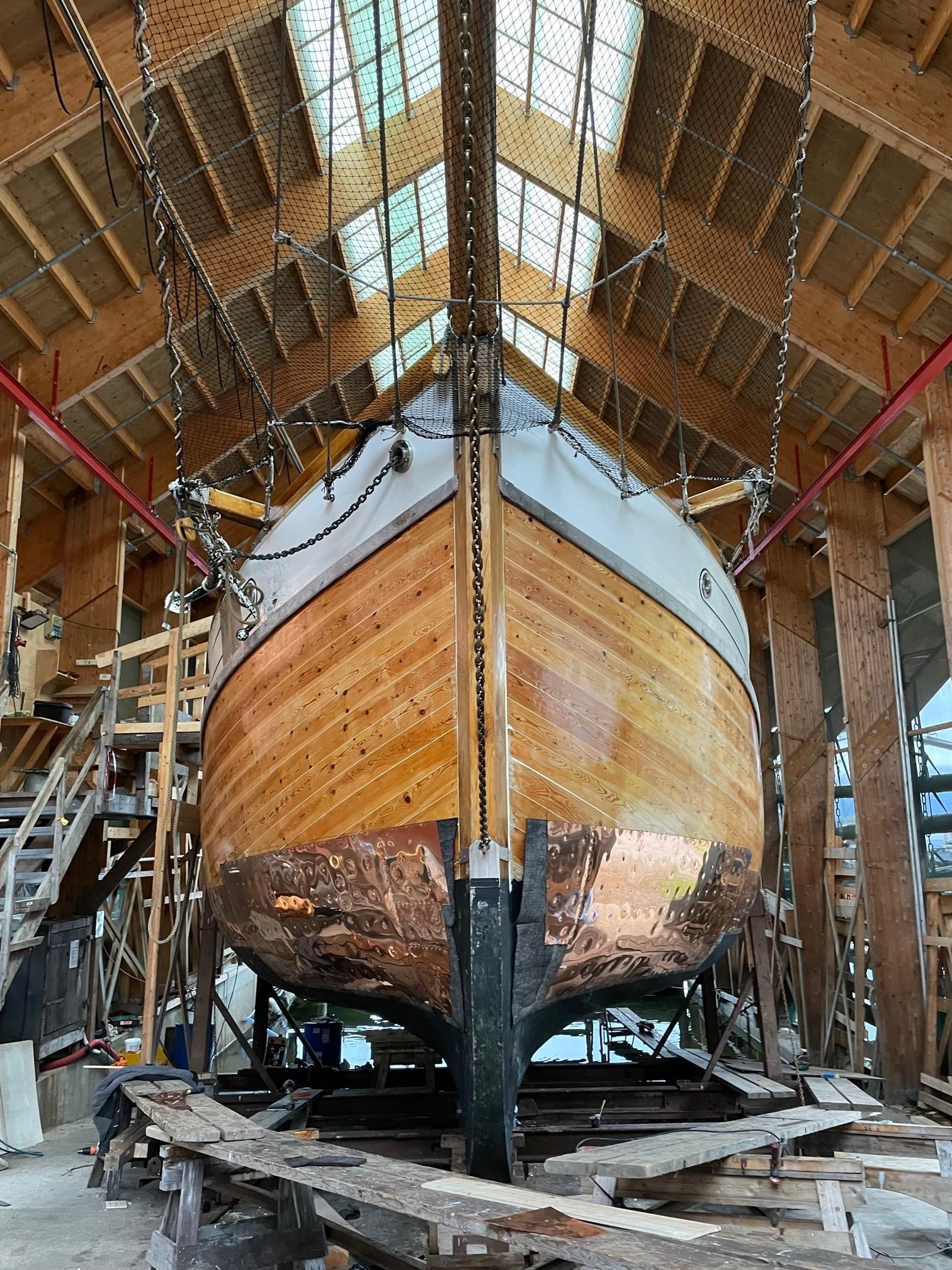 A large wooden boat under restoration inside the workshop building at Hardanger Maritime Center.