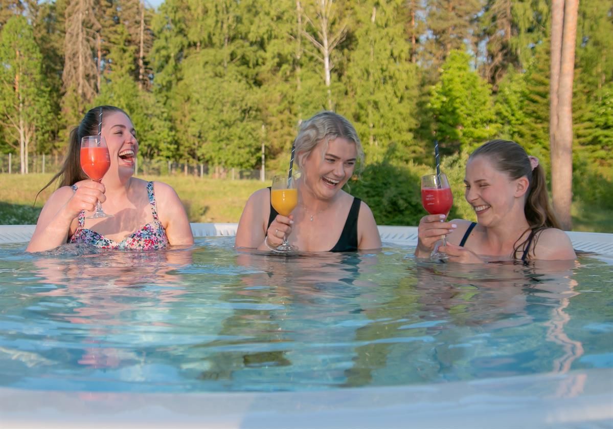 Tre jenter med moctails i utendørs basseng