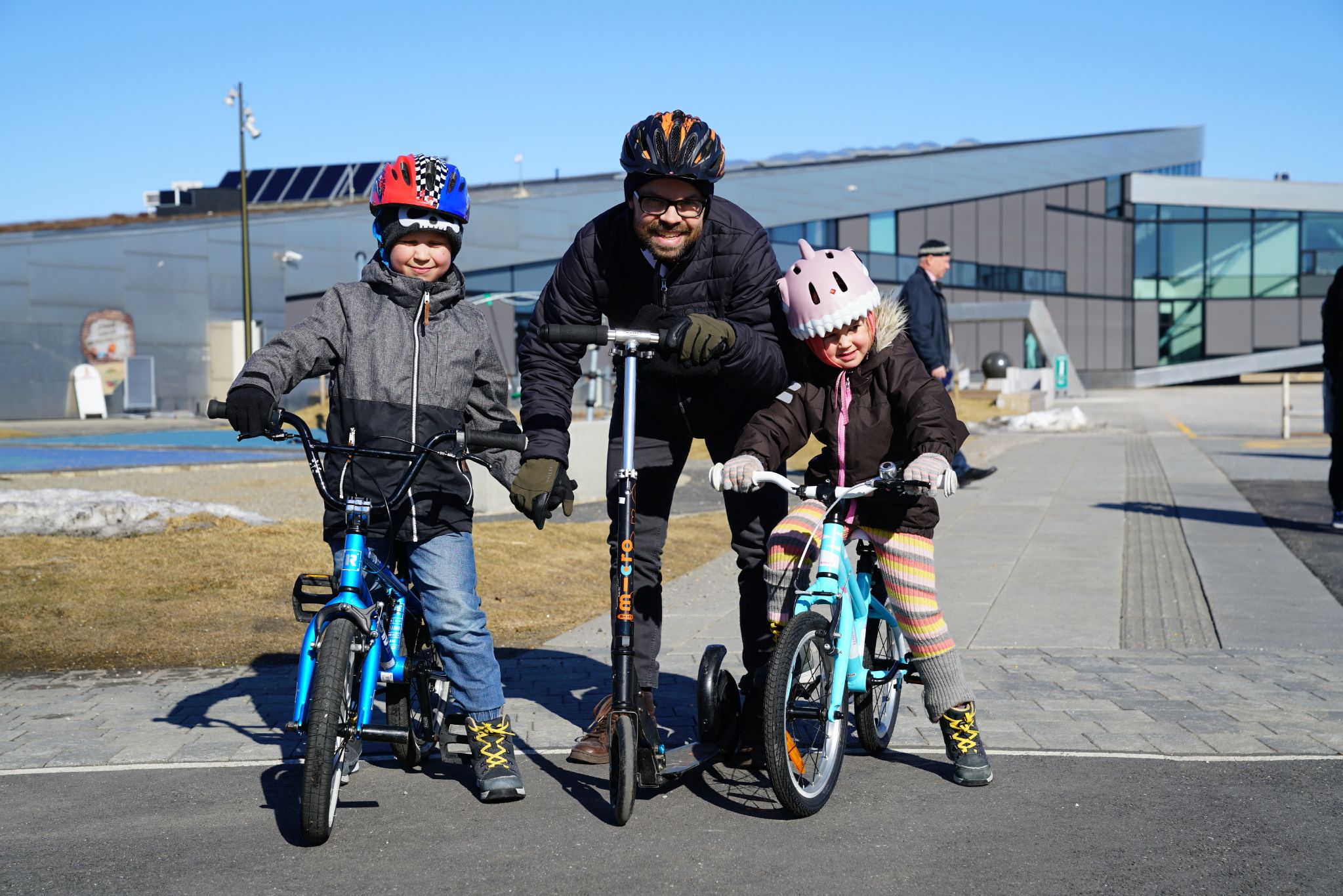 A girl and a boy on a bike and a man on a scooter test out the activity park 