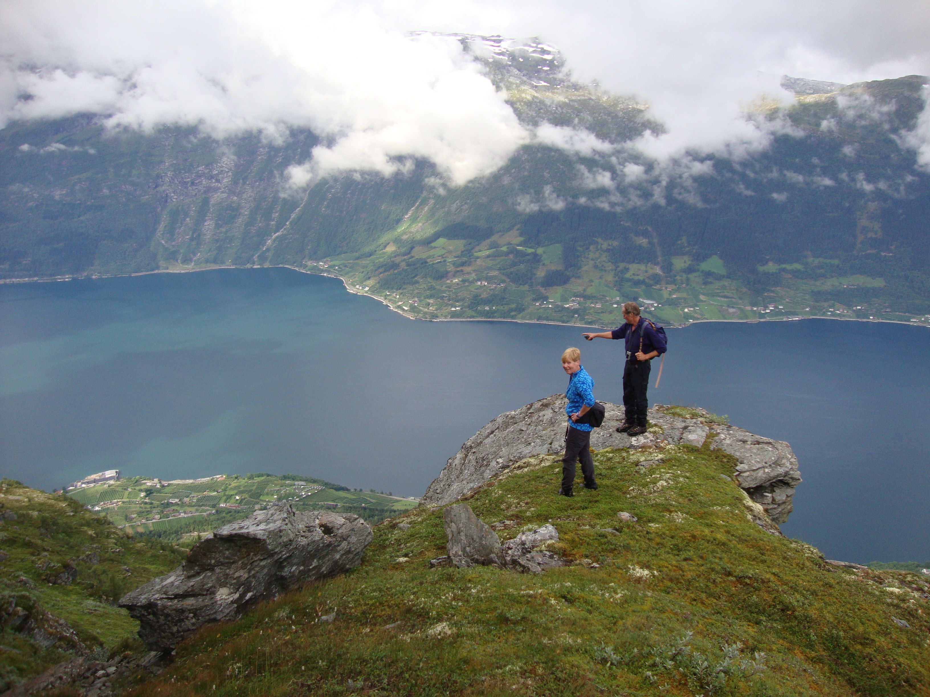 Two hikers at the top of a mountain on Dronningstien, overlooking the Hardangerfjord.
