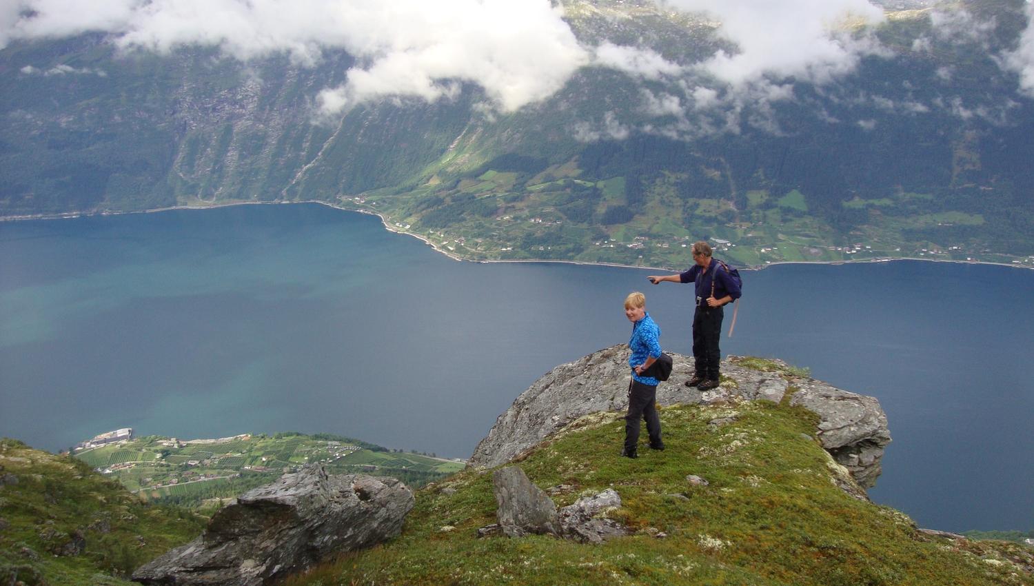 Two hikers at the top of a mountain on Dronningstien, overlooking the Hardangerfjord.