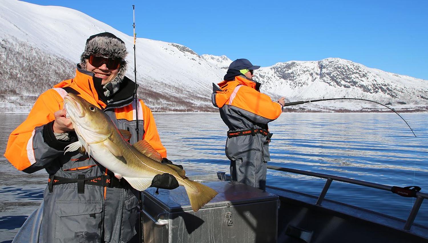 One guest holding a fish and a guest fishing