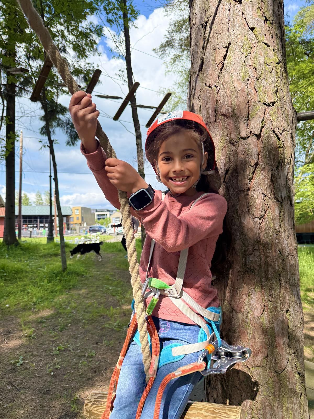  A child holding onto a rope, preparing to climb or swing in the obstacle course.
