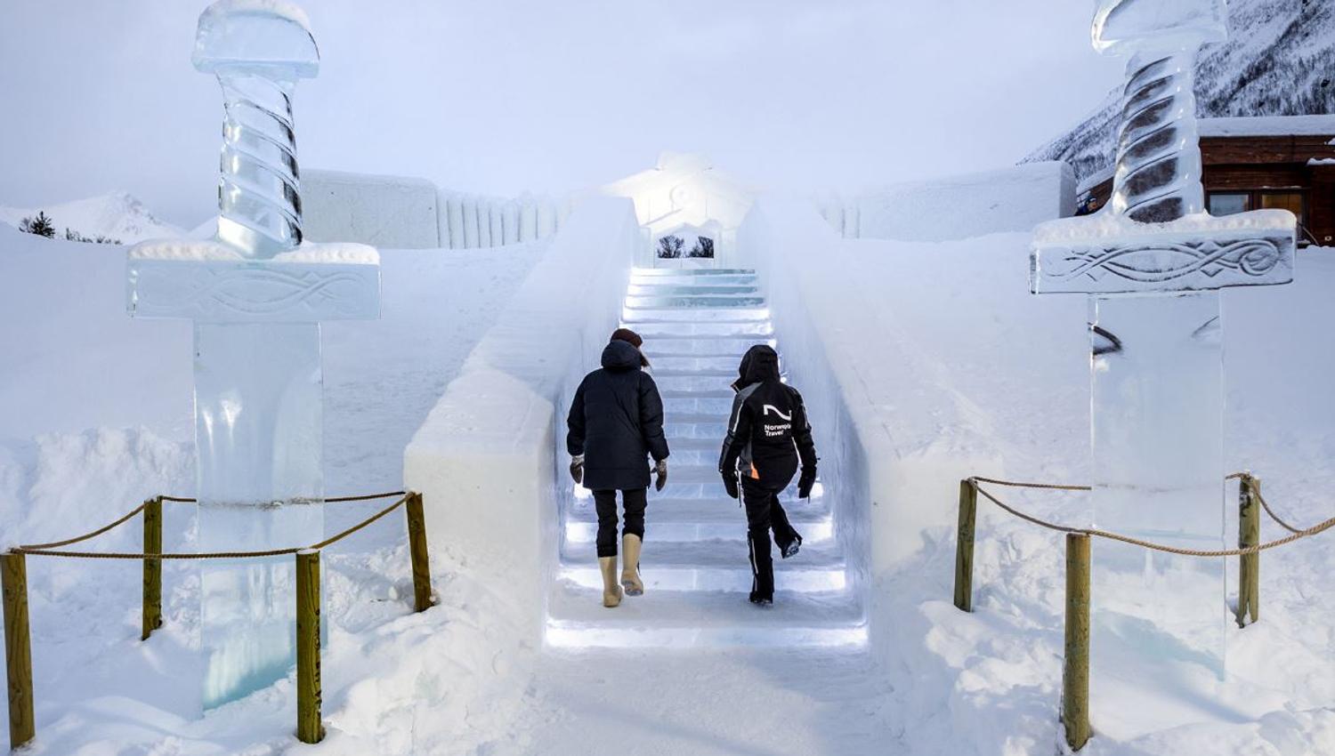 Guest walk up the lit steps towards the entrance of the Ice Domes. They are also carved from the snow.