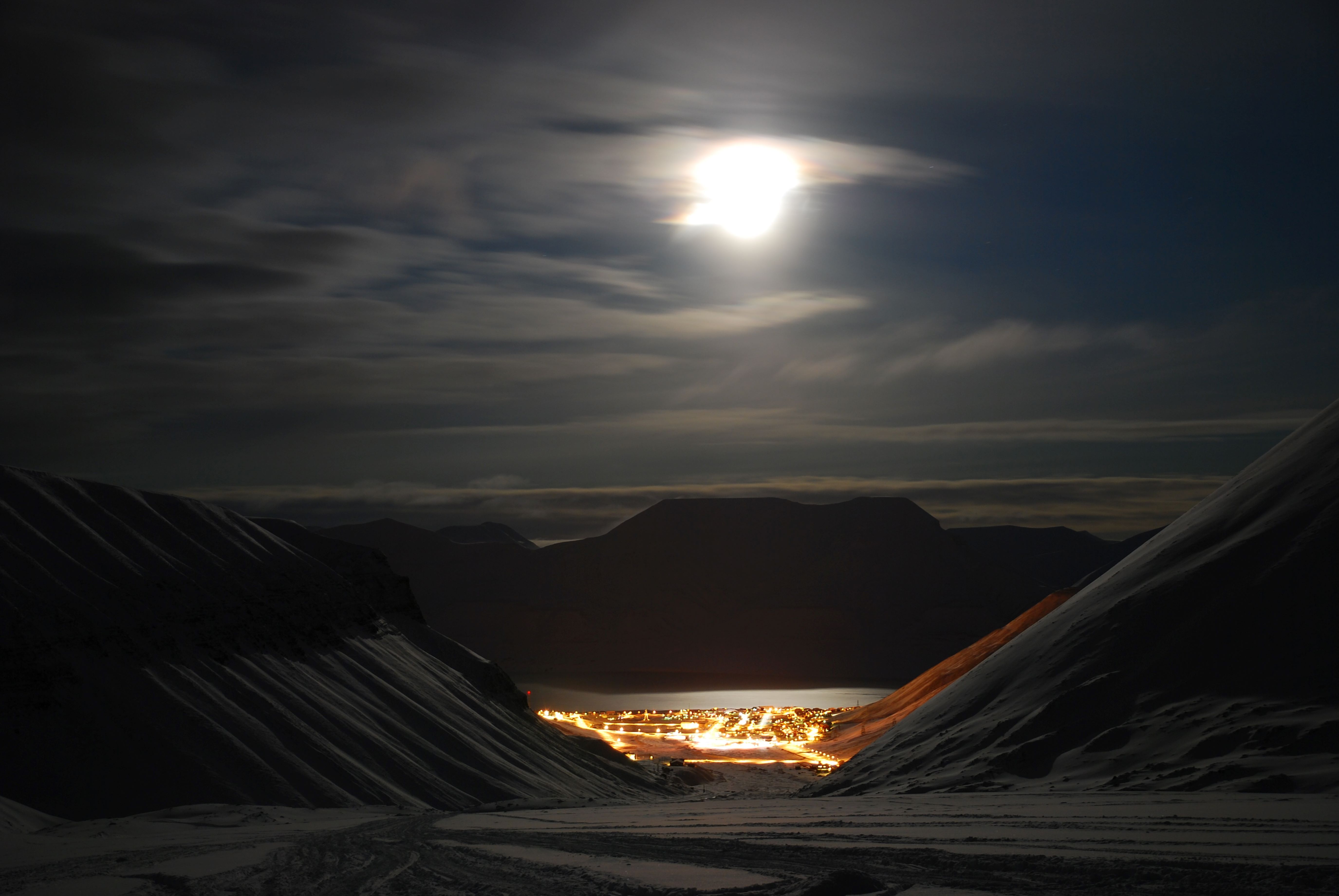 Longyearbyen at the end of the valley. The moonlight lights up the surrounding mountains.