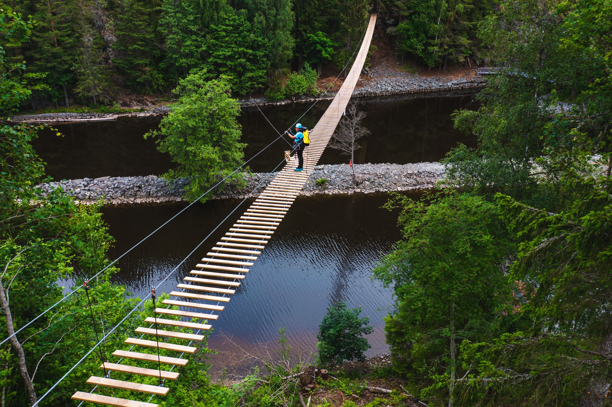 En person som krysser hengebroa, bildet er tatt fra lufta.