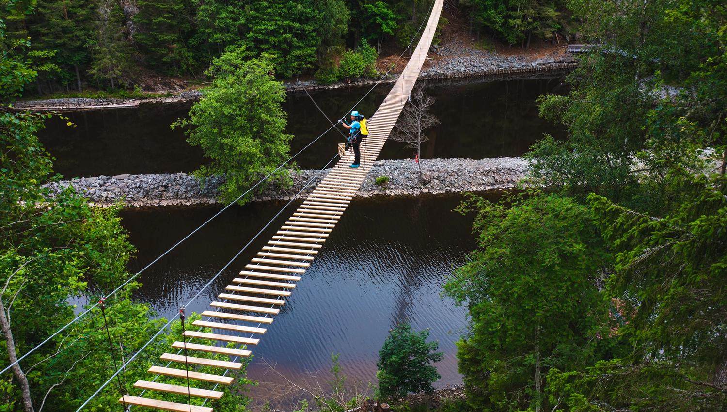 En person som krysser hengebroa, bildet er tatt fra lufta.