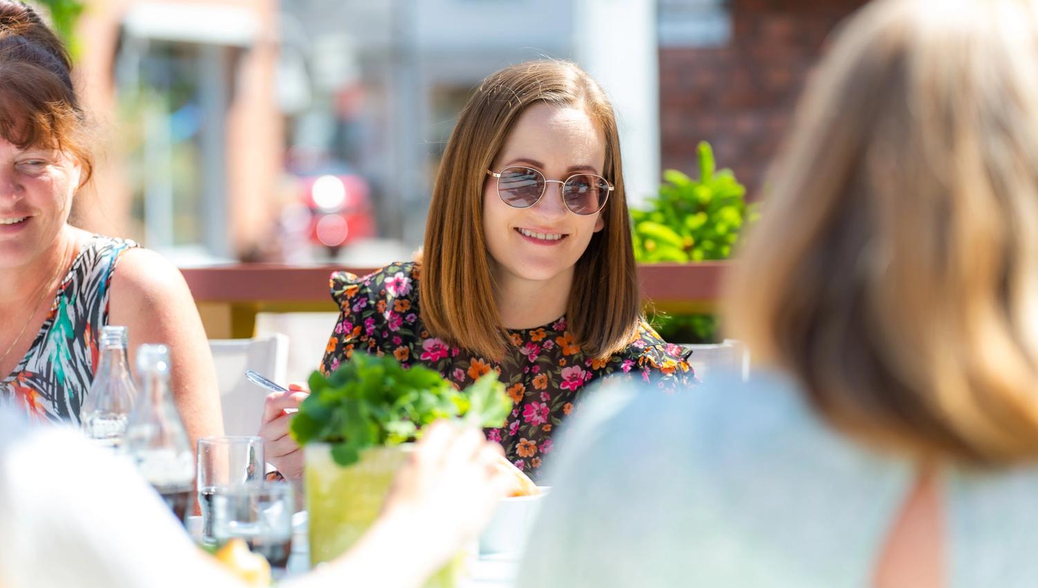 Flere unge damer nyter maten fra Villa Welhaven på deres flotte platting ute i solen