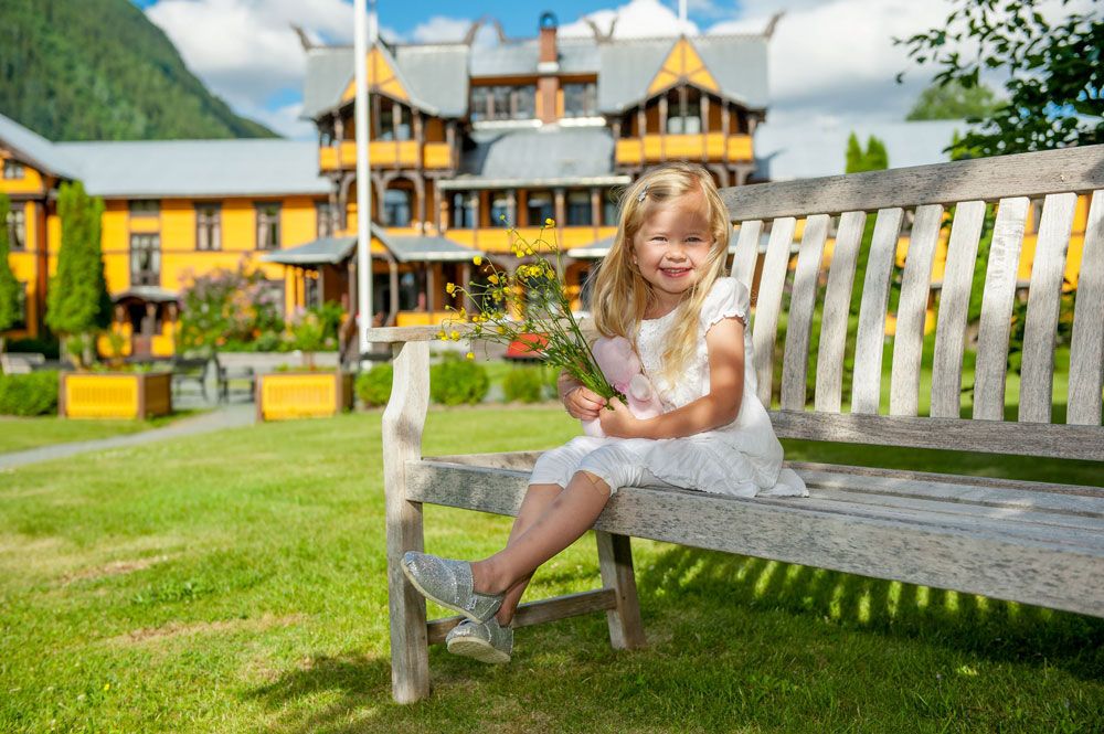 liten jente sitter på en benk foran Dalen Hotel