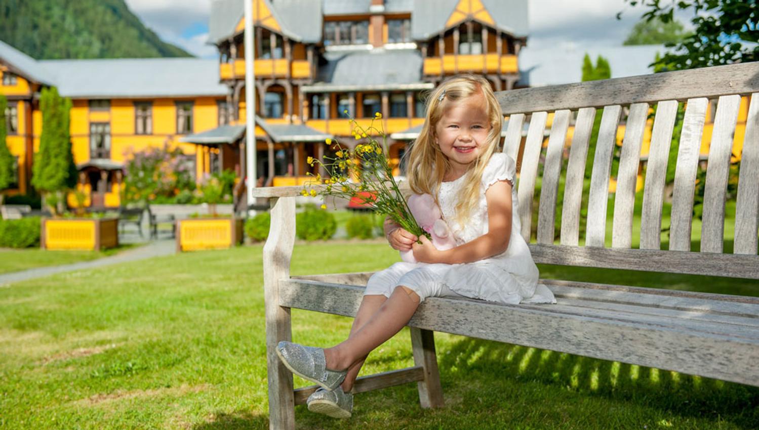 liten jente sitter på en benk foran Dalen Hotel