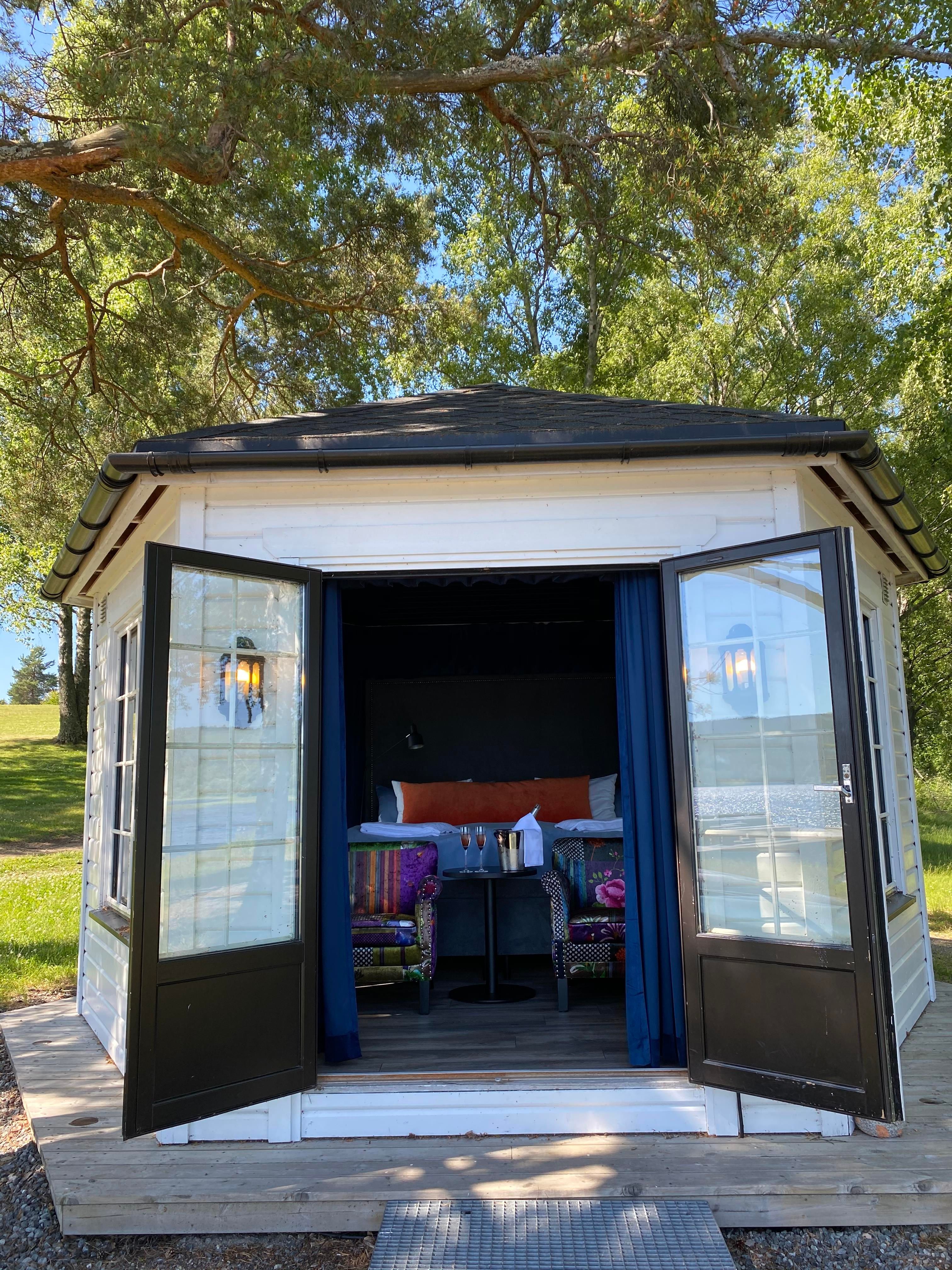 strandhus sett utenfra med stoler og seng