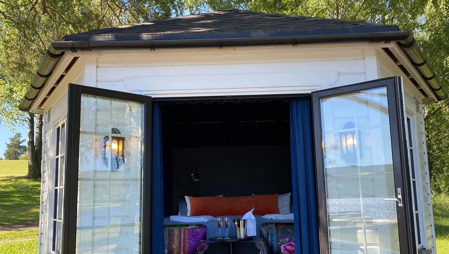 strandhus sett utenfra med stoler og seng