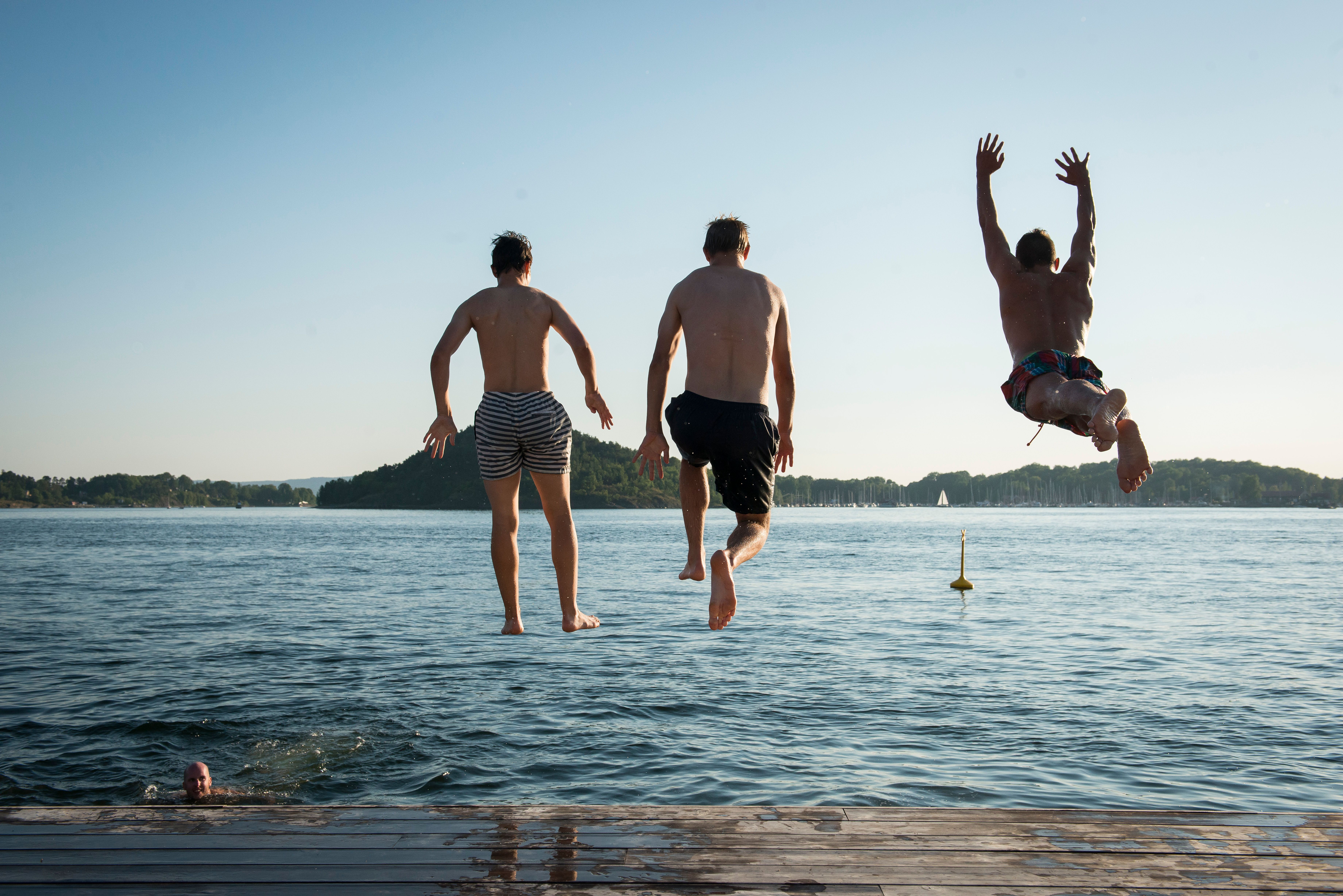 tre personer som hopper i havet