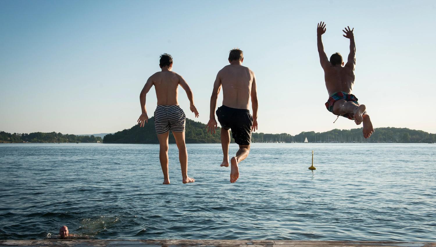 tre personer som hopper i havet