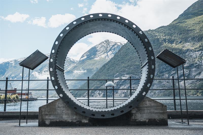 Utandørs utstilling ved Kraftmuseet med ein stor turbinring og utsikt over fjorden og fjella i Hardanger.