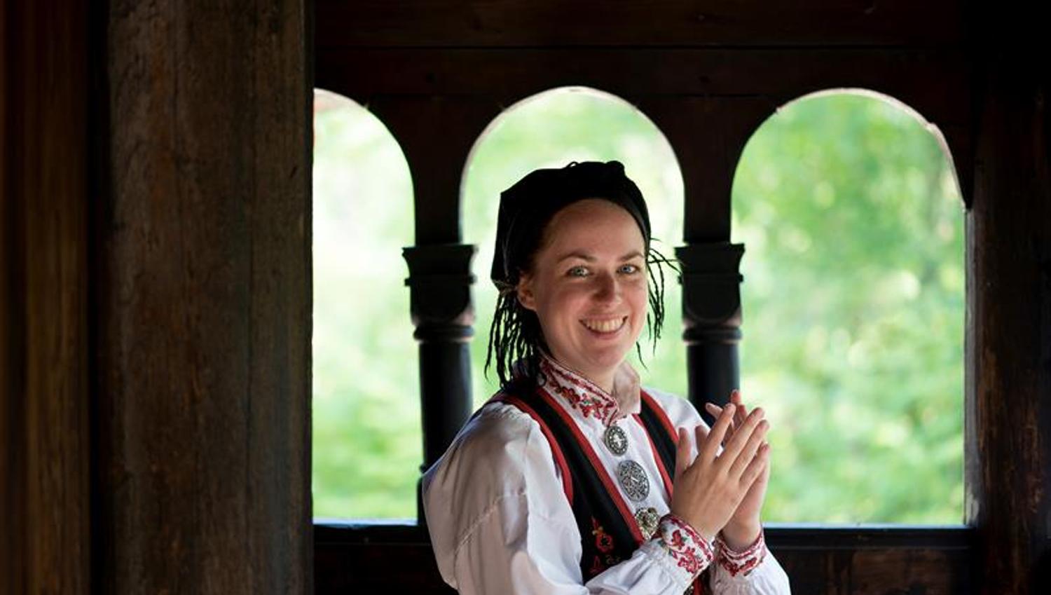 Kvinne i bunad ved Gol stavkirke. Norsk Folkemuseum