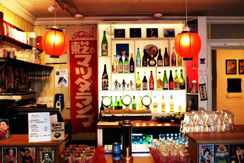 Bar area with rice lamps, various beverages and glasses.