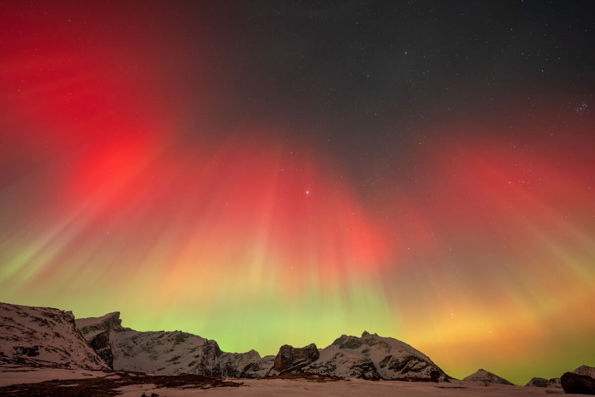 Rødt, oransje og grønt nordlys dannet en krone over fjellene.