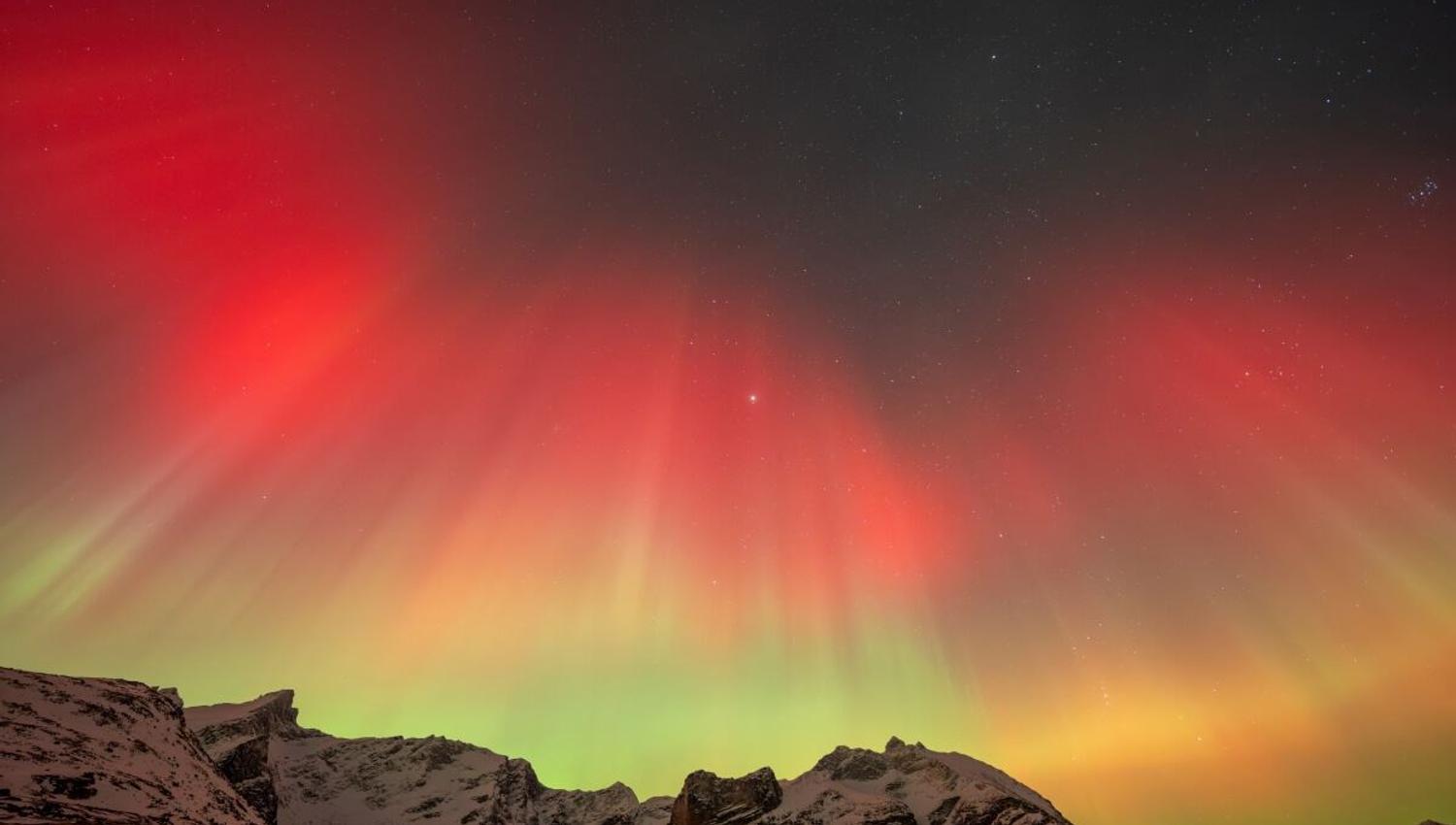 Rødt, oransje og grønt nordlys dannet en krone over fjellene.
