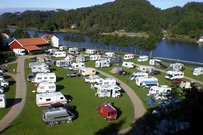 Bobil/Campingvogn på rekke og rad, med vei i mellom rekkene, Mandalselva like ved.