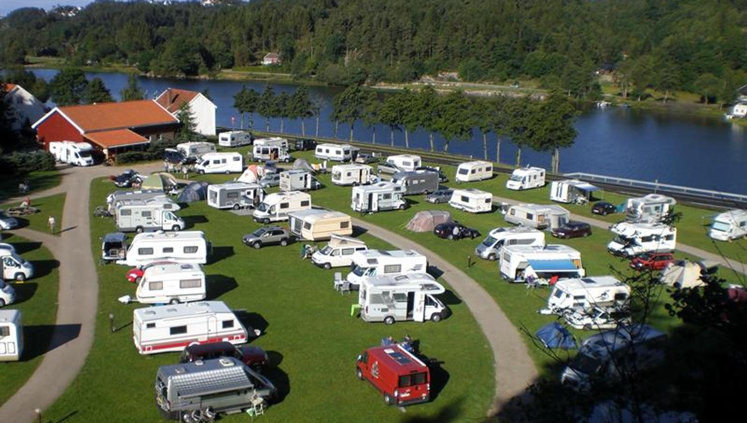 Bobil/Campingvogn på rekke og rad, med vei i mellom rekkene, Mandalselva like ved.