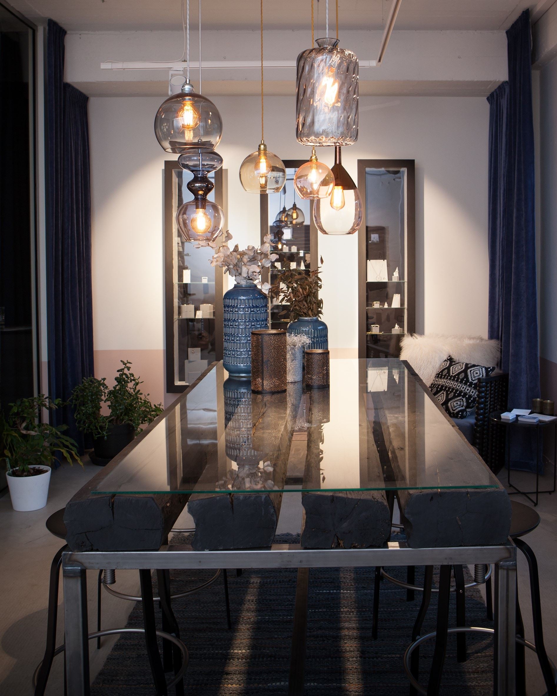 Moderne spisestue med glassbord, hengelamper og blå vaser
