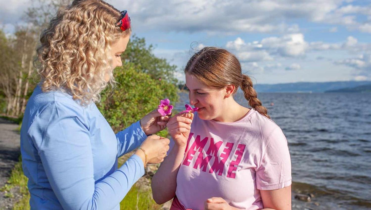 To personer står ved vannkanten og ser på en liten blomst sammen.