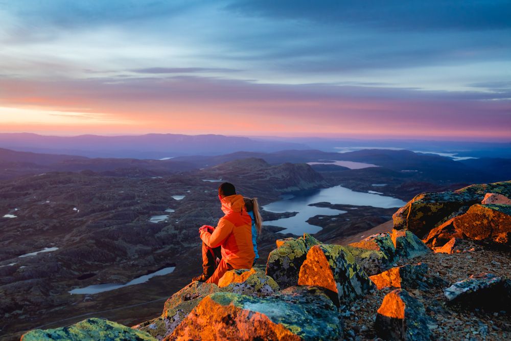 par sitter på toppen av Gaustatoppen i kveldsola