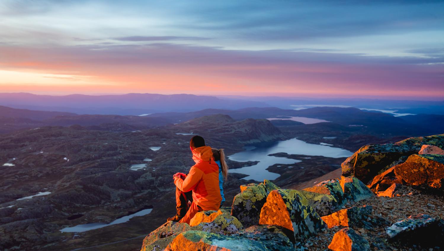 par sitter på toppen av Gaustatoppen i kveldsola