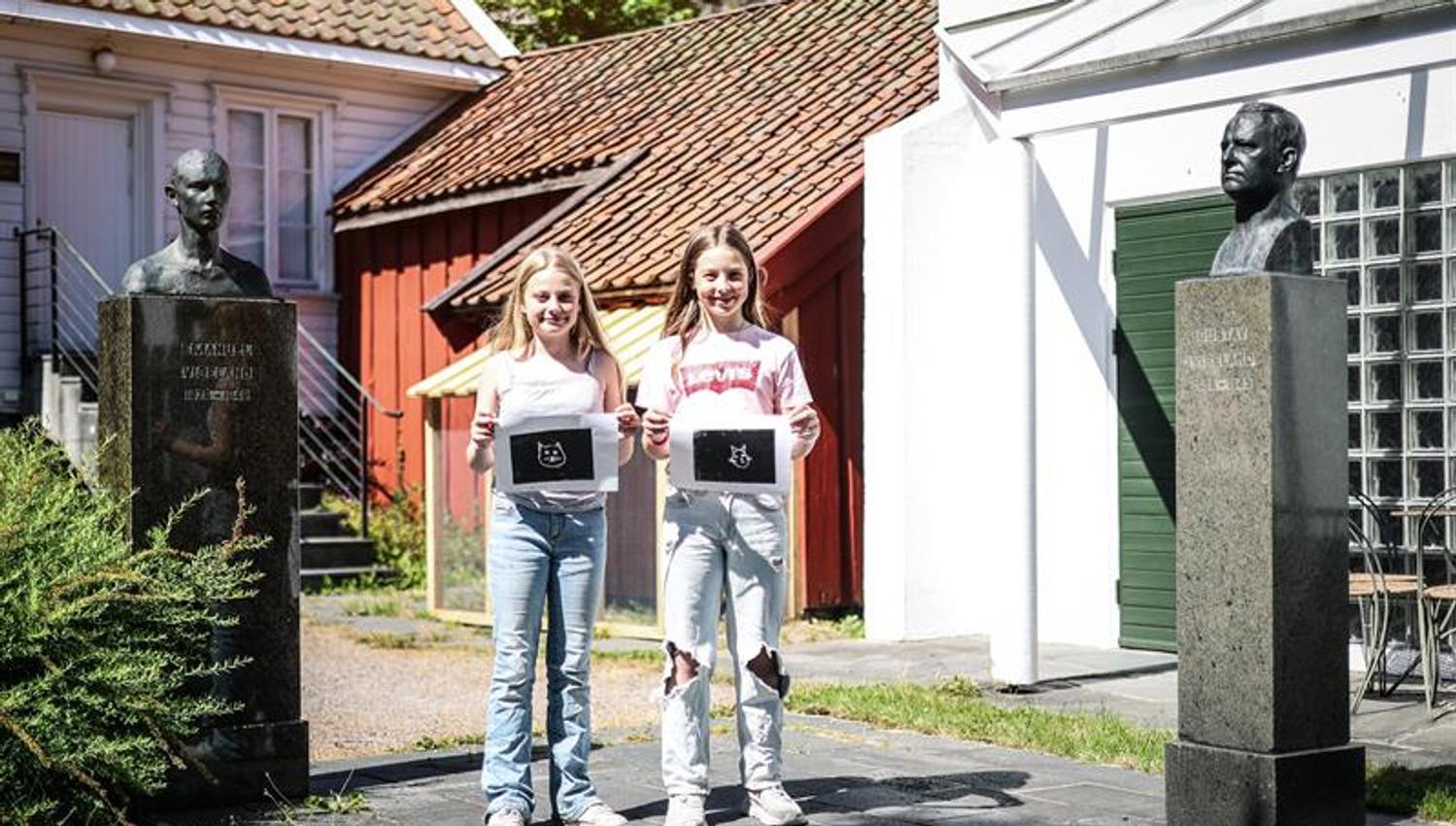 To smilende jenter viser frem tresnittet de har laget