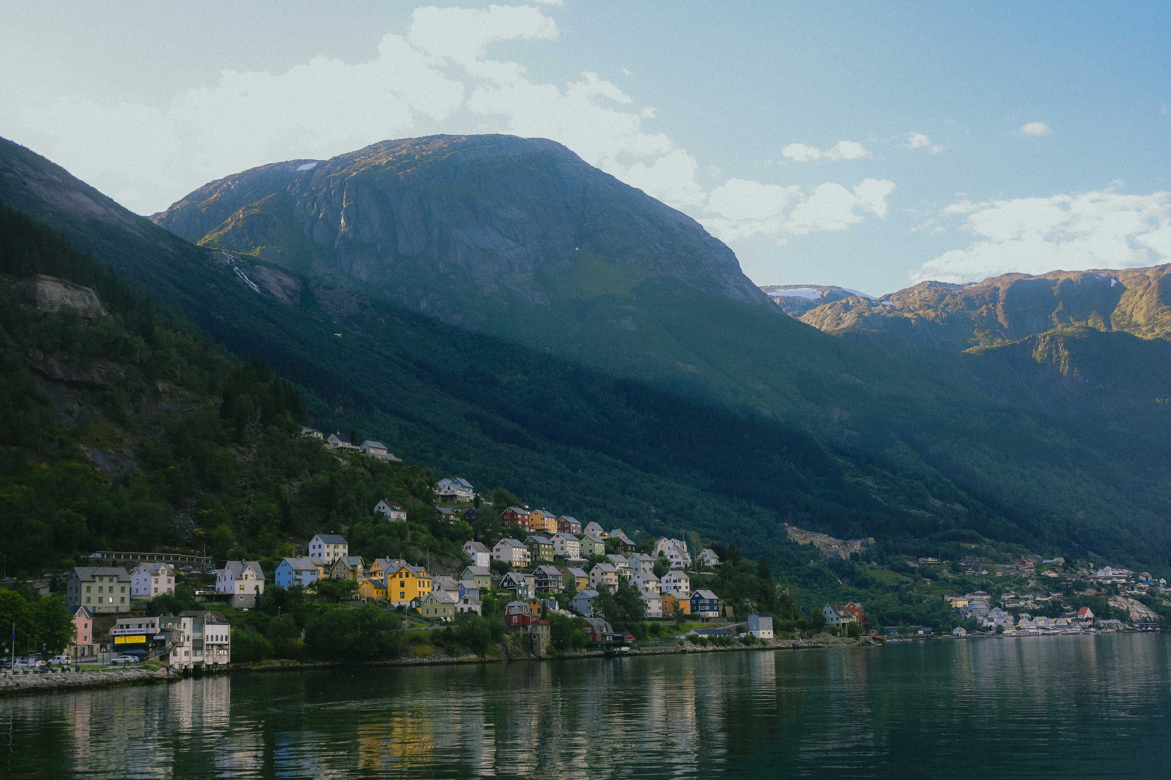 Kveldslys over Odda med fargerike hus spredt langs de bratte åssidene.