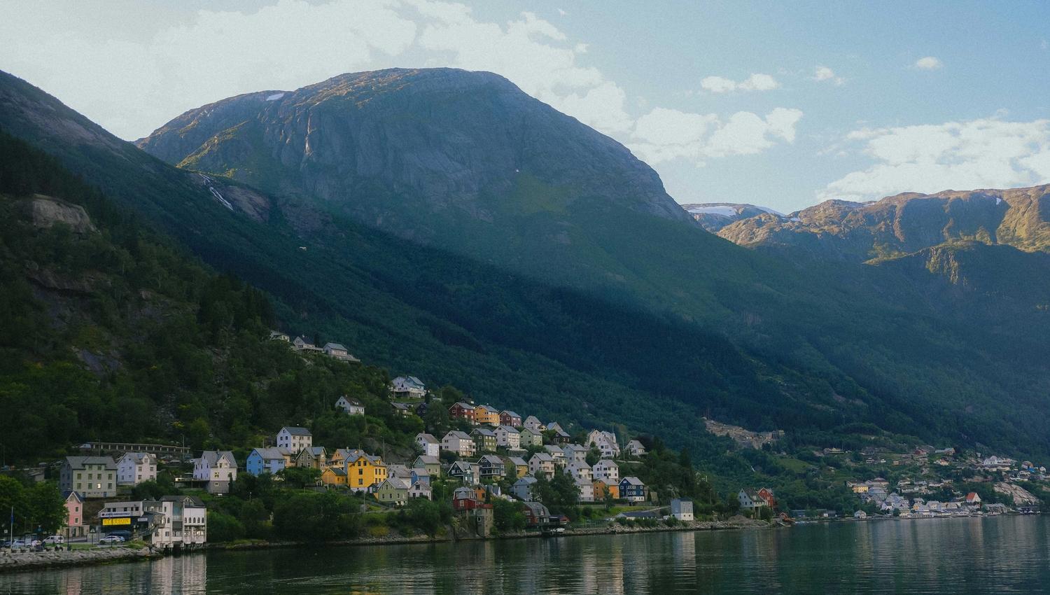 Kveldslys over Odda med fargerike hus spredt langs de bratte åssidene.