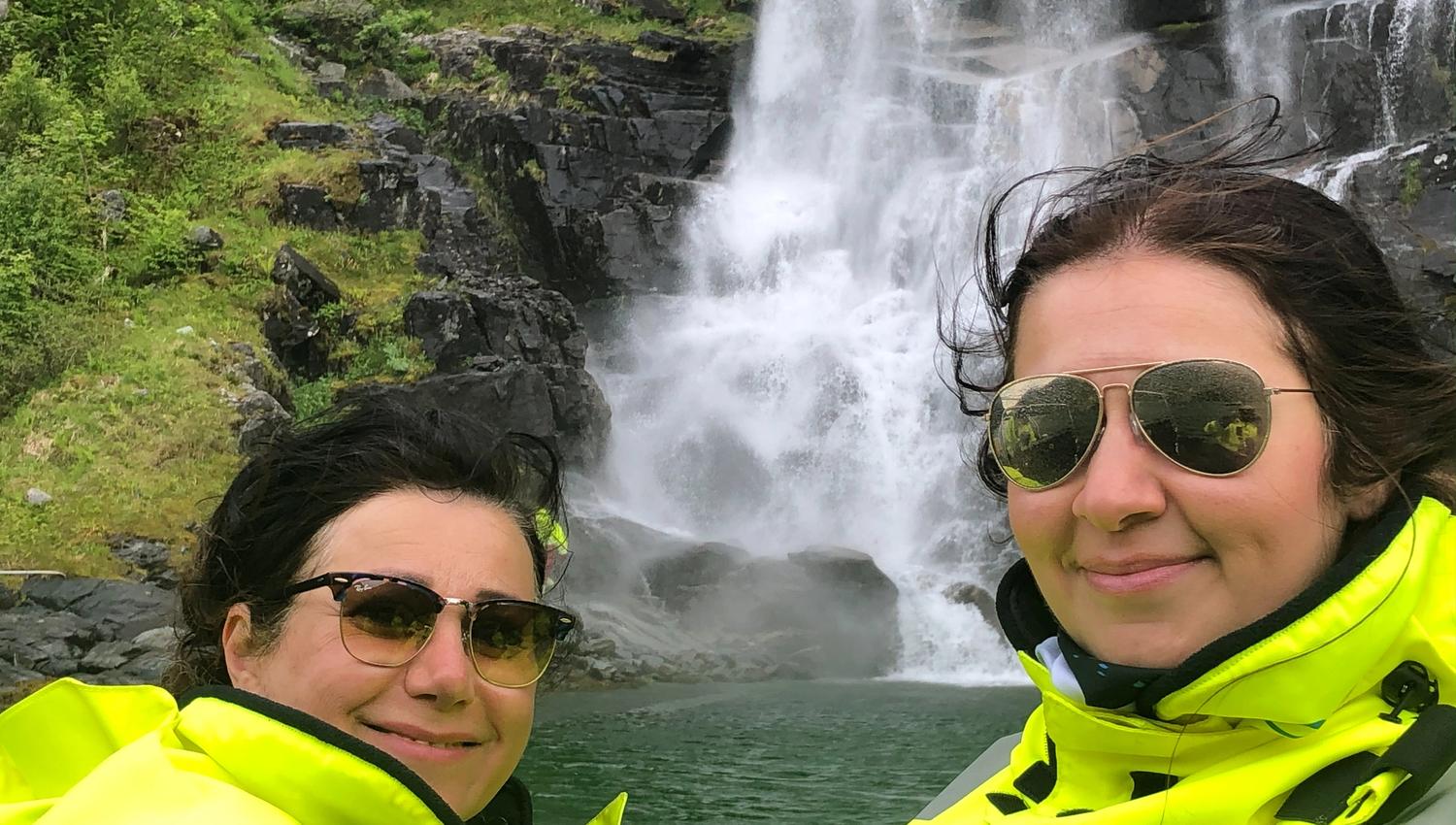 To turistar i gule drakter nyt synet av eit buldrande fossefall på RIB-safari i Hardanger.