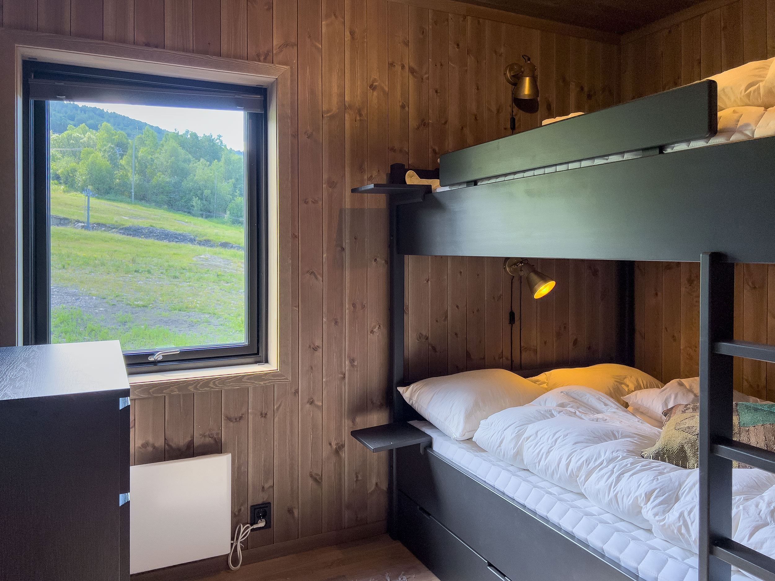 A bunk bed in a room with a window and grass.