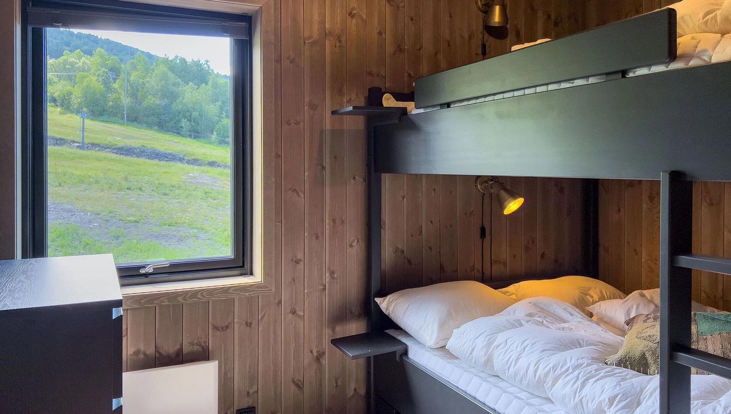 A bunk bed in a room with a window and grass.
