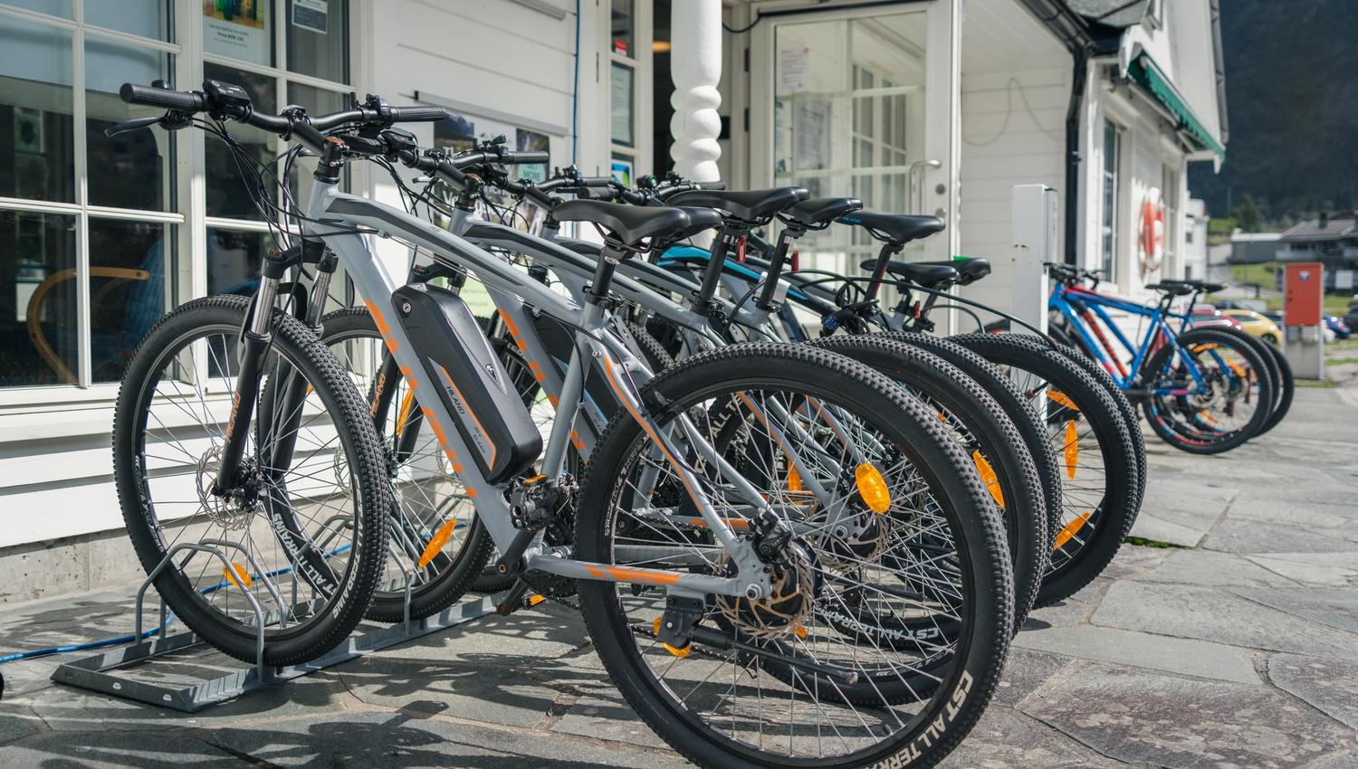A few e-bikes and regular bikes on a bike rack outside the tourist office.